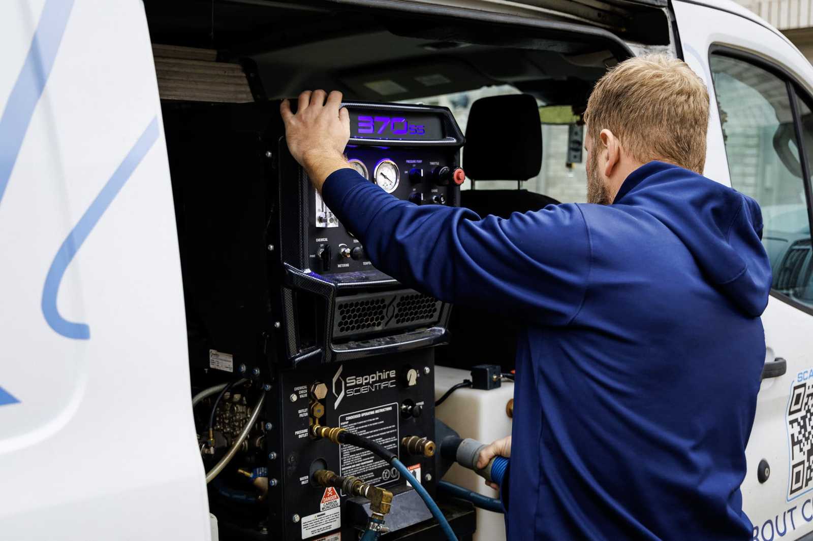 Technician operating a truck-mounted carpet cleaning machine in the van